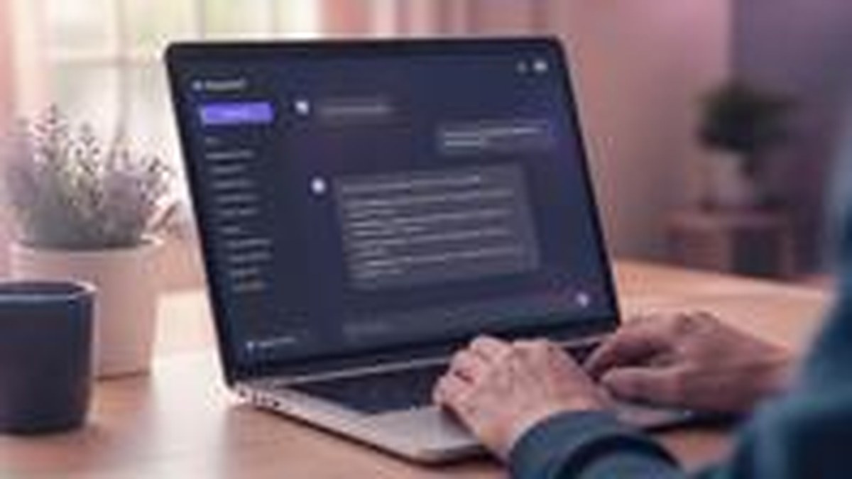 Pessoa digitando em notebook com interface de assistente de IA na tela