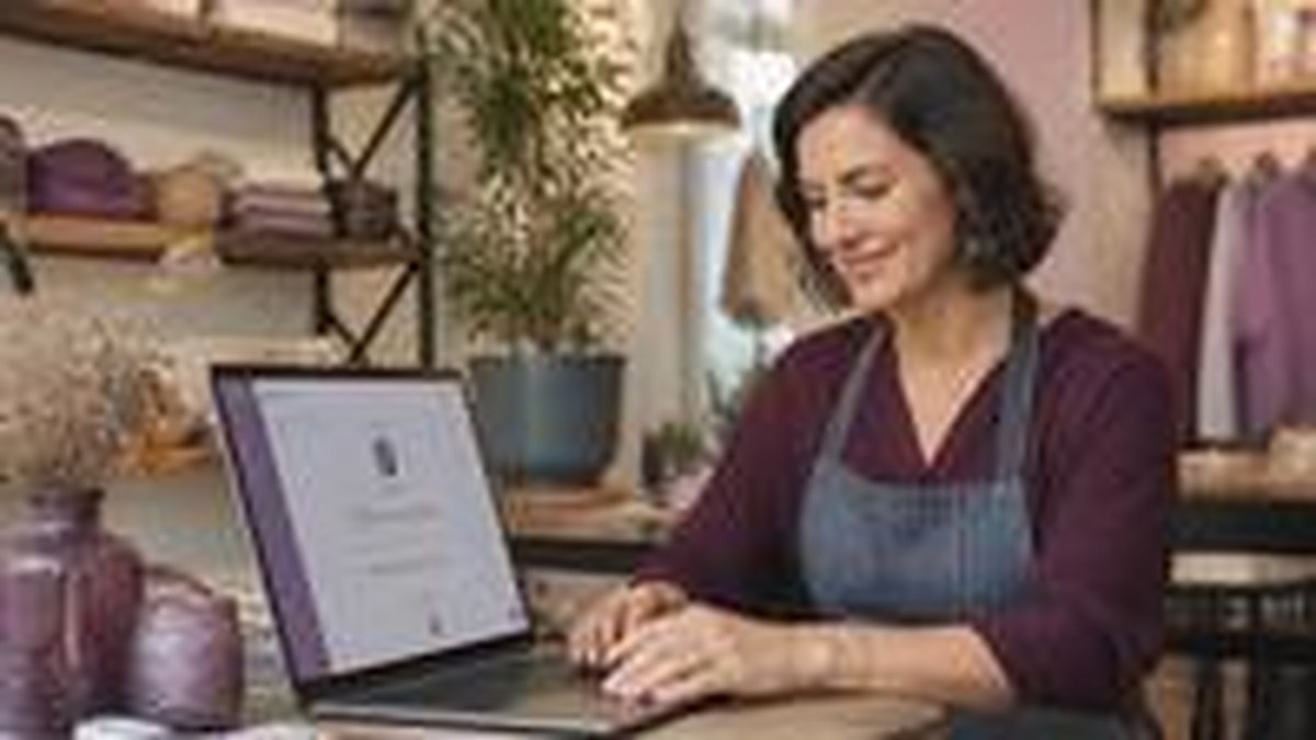 Pequeno empreendedor sorrindo ao usar notebook com assistente de IA