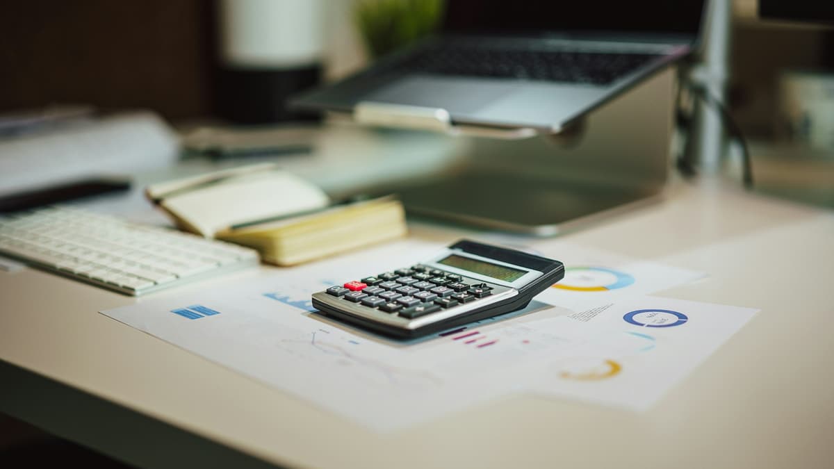 Calculadora ao lado de um notebook sobre a mesa de trabalho